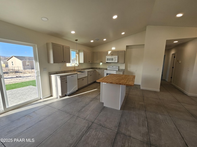 kitchen with lofted ceiling, white appliances, sink, hanging light fixtures, and a kitchen island