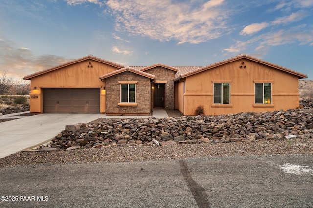 view of front of house featuring driveway, a tiled roof, and an attached garage