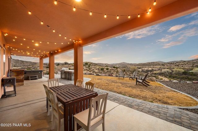 view of patio featuring outdoor dining area, a mountain view, and a hot tub