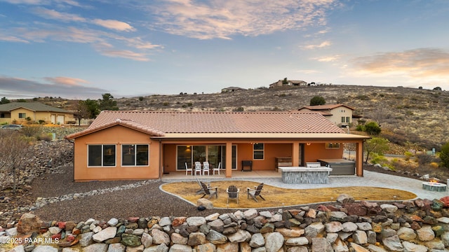 back of property featuring a patio, stucco siding, a fire pit, a jacuzzi, and a tiled roof