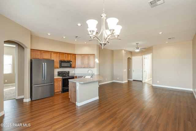 kitchen featuring black appliances, a kitchen island with sink, sink, pendant lighting, and dark hardwood / wood-style floors