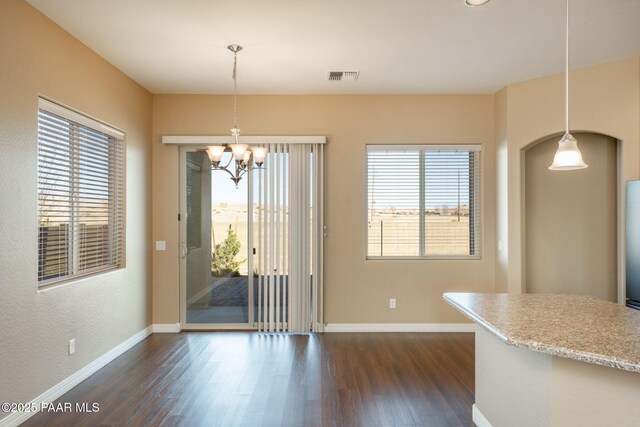 unfurnished dining area featuring dark wood-type flooring and an inviting chandelier