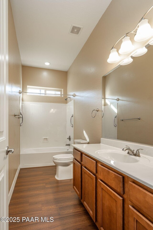 full bathroom with toilet, hardwood / wood-style flooring, washtub / shower combination, and vanity