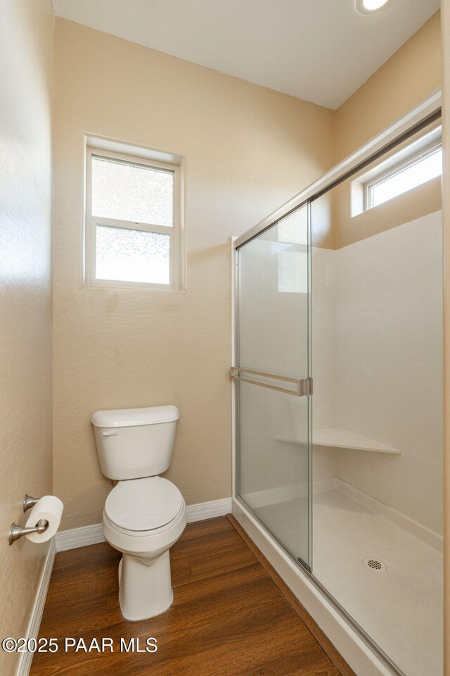 bathroom featuring a shower with shower door, toilet, and wood-type flooring