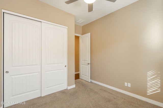 unfurnished bedroom featuring light carpet, a closet, and ceiling fan