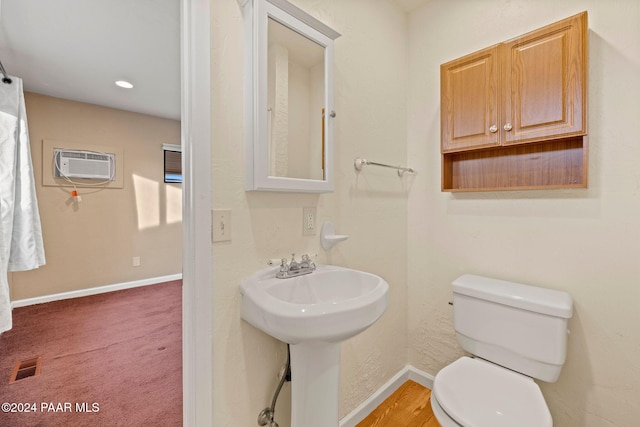 bathroom with a wall mounted air conditioner, toilet, and sink