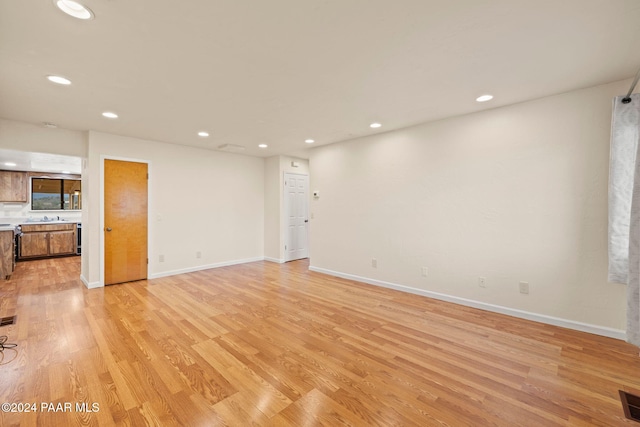 unfurnished living room featuring light wood-type flooring and sink