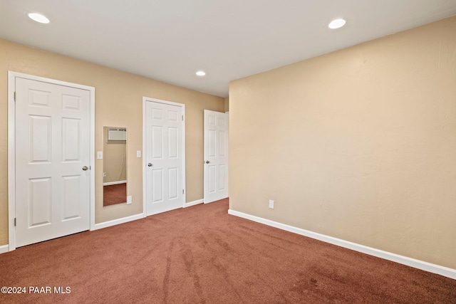 unfurnished bedroom with an AC wall unit and carpet