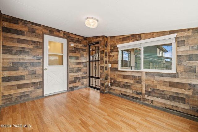 spare room with lofted ceiling, light wood-type flooring, and wooden walls