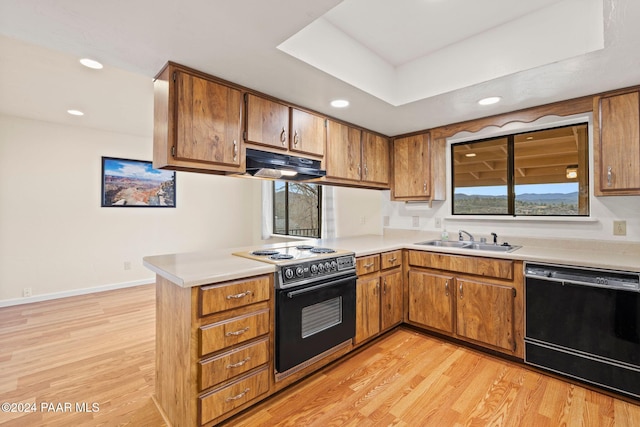 kitchen with kitchen peninsula, sink, light hardwood / wood-style floors, and black appliances