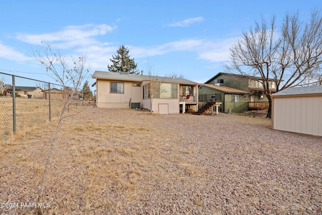 back of house featuring central AC unit and a storage unit