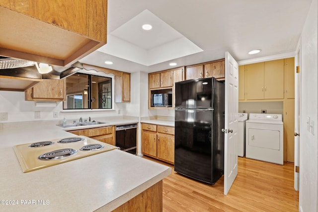 kitchen with kitchen peninsula, light wood-type flooring, sink, washer and dryer, and black appliances