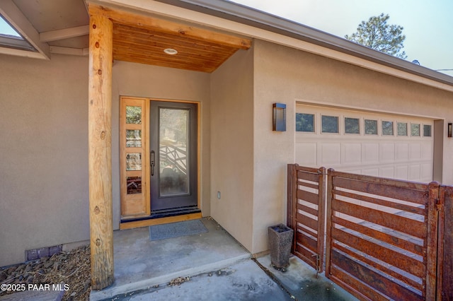 doorway to property featuring visible vents, an attached garage, and stucco siding