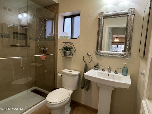 bathroom featuring toilet, a stall shower, and a sink