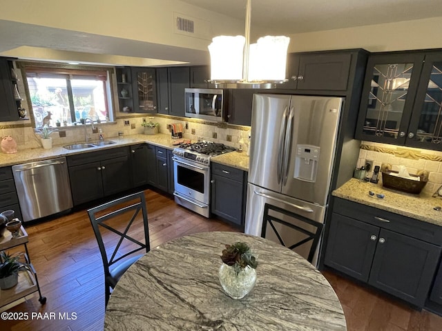 kitchen with stainless steel appliances, light stone counters, decorative backsplash, and a sink