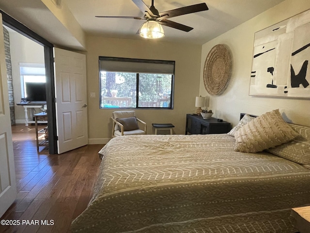 bedroom featuring baseboards, a ceiling fan, multiple windows, and dark wood-type flooring
