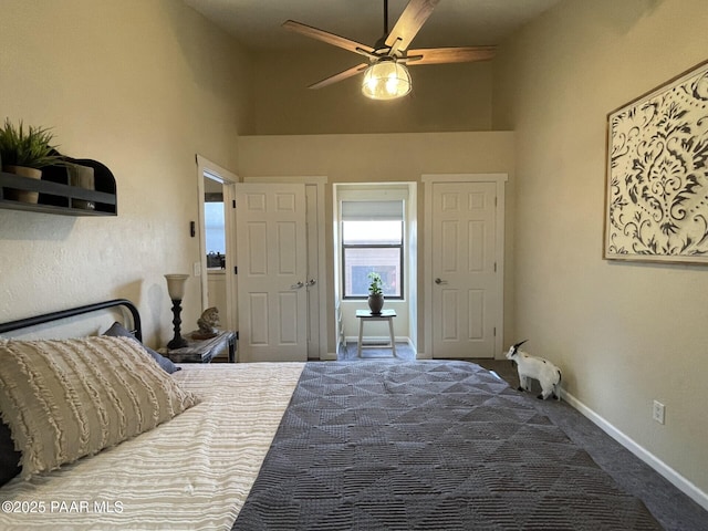 carpeted bedroom featuring a towering ceiling, a ceiling fan, and baseboards