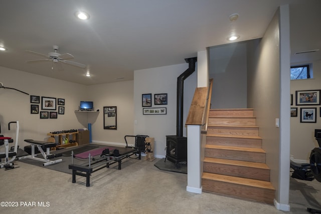 workout area with a wood stove, recessed lighting, carpet flooring, a ceiling fan, and baseboards