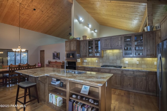 kitchen featuring a breakfast bar area, a sink, appliances with stainless steel finishes, wood finished floors, and backsplash