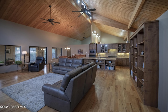 living room with high vaulted ceiling, beamed ceiling, ceiling fan with notable chandelier, and light wood finished floors