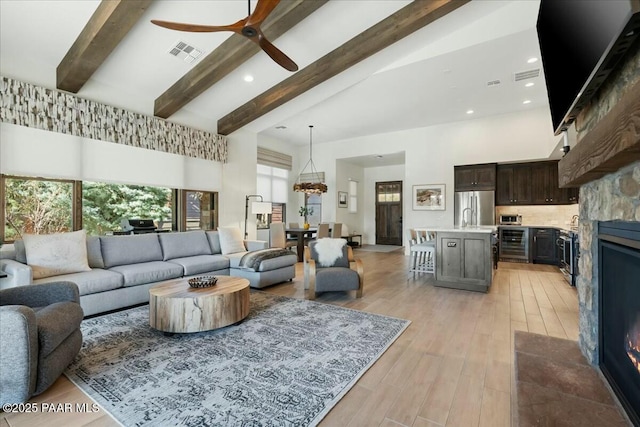 living room featuring lofted ceiling with beams, ceiling fan, wine cooler, and light wood-type flooring