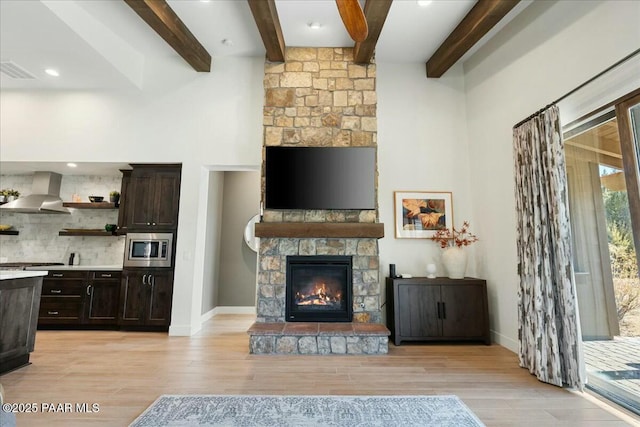 unfurnished living room with beamed ceiling, light wood-type flooring, and a fireplace