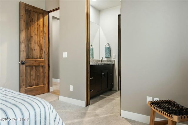 carpeted bedroom with ensuite bathroom and sink