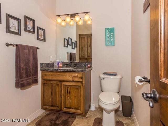 bathroom with toilet, vanity, baseboards, and tile patterned flooring