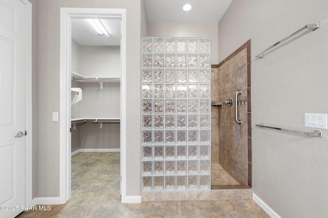 bathroom with a walk in closet, baseboards, and a walk in shower