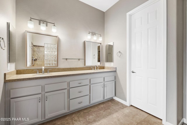 full bath featuring double vanity, a sink, and baseboards