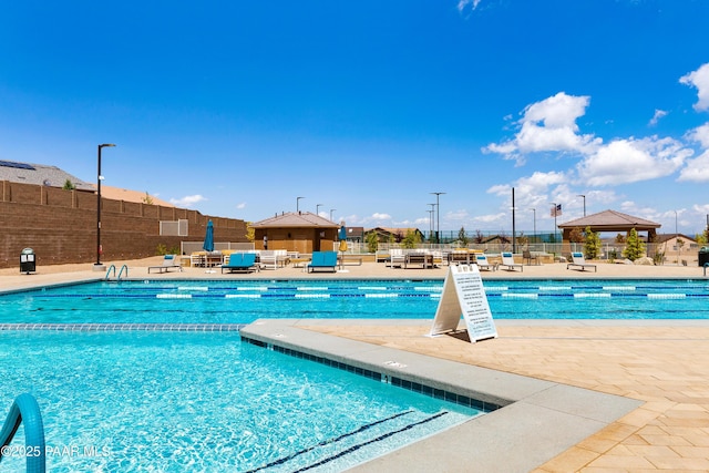 pool with a patio area and fence