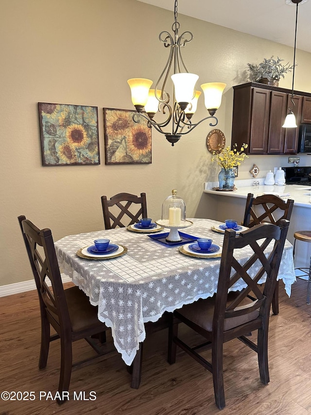 dining space with baseboards, a notable chandelier, and wood finished floors