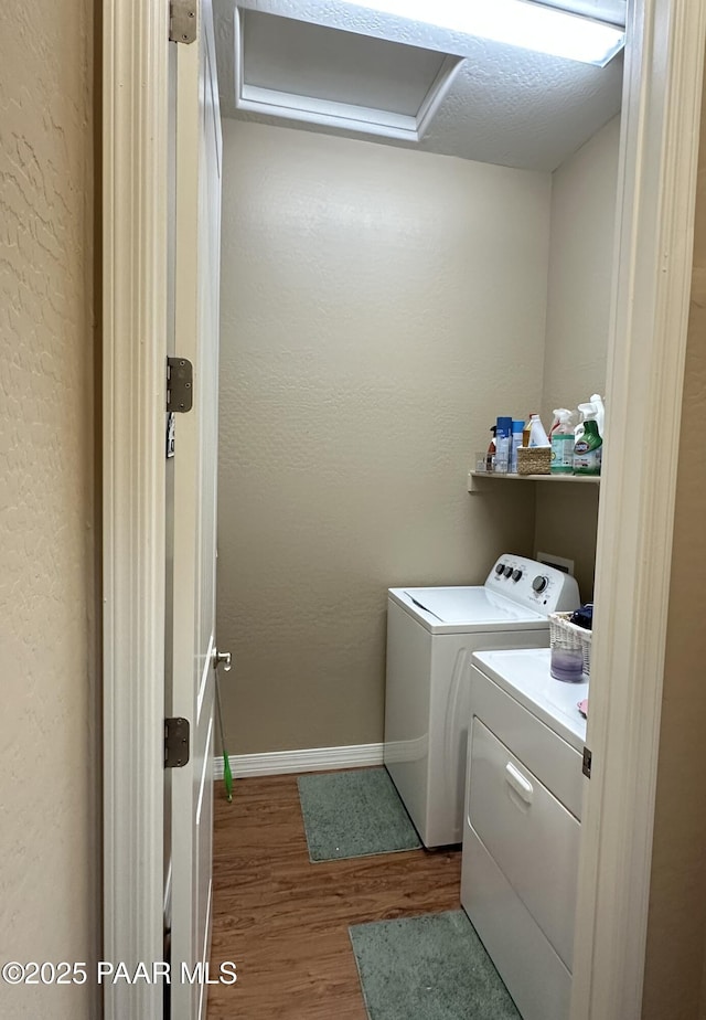 laundry room featuring wood finished floors, baseboards, attic access, laundry area, and washing machine and clothes dryer