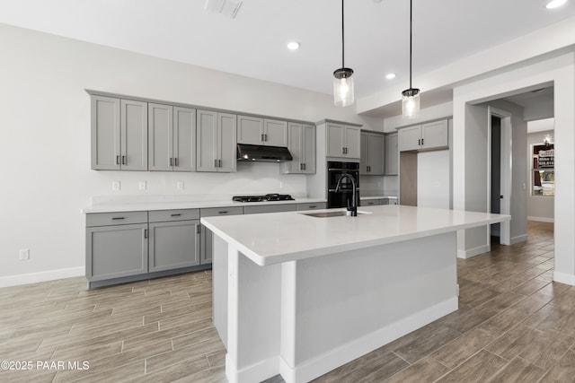 kitchen with gray cabinets, an island with sink, sink, and gas cooktop