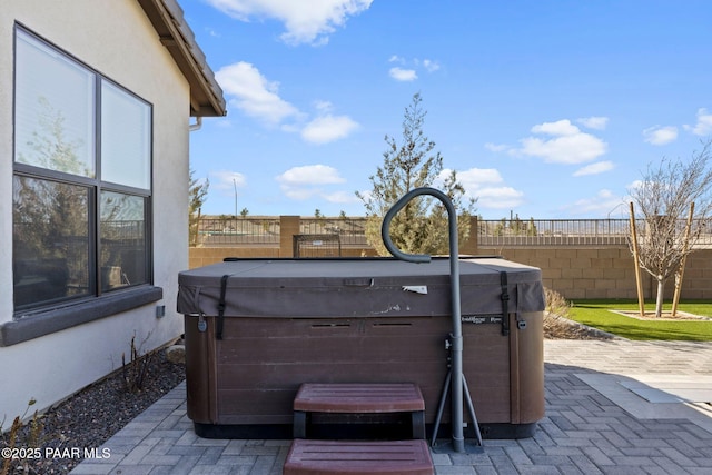 view of patio featuring fence and a hot tub