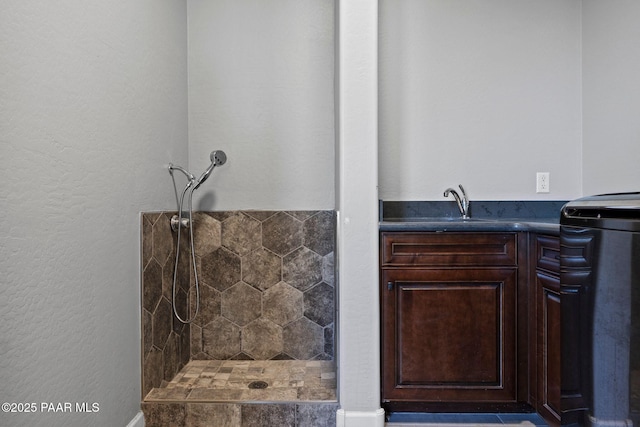 full bath with a tile shower and a sink