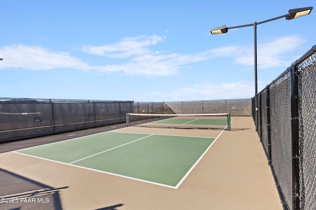 view of tennis court with community basketball court and fence