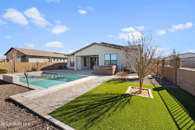 rear view of property featuring a hot tub, a lawn, a patio, a fenced backyard, and stucco siding