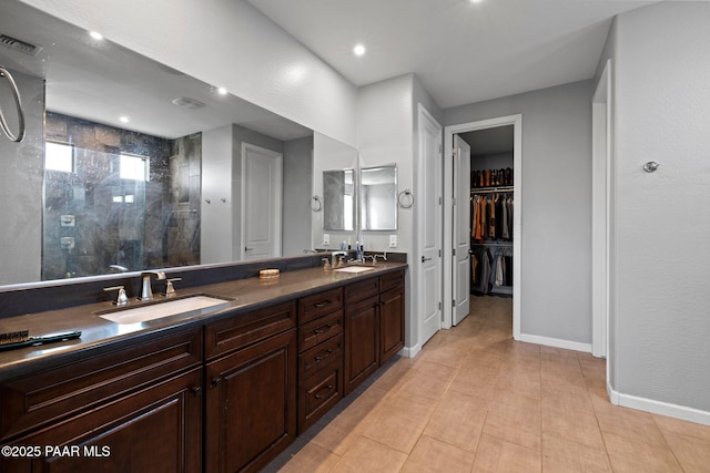 full bath with a sink, visible vents, baseboards, double vanity, and walk in shower