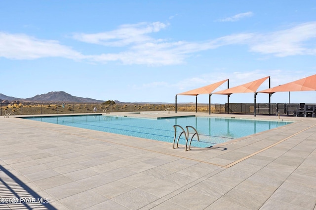 community pool featuring a patio area, fence, and a mountain view