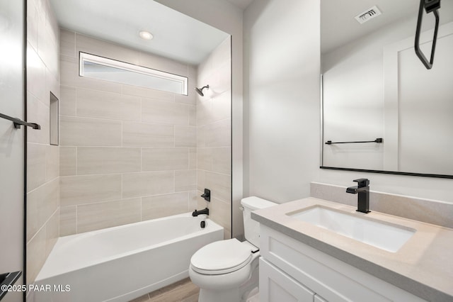 bathroom featuring shower / washtub combination, visible vents, toilet, vanity, and wood finished floors