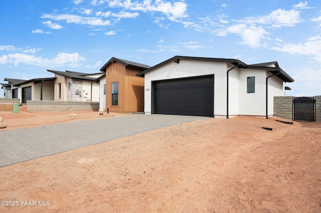 view of front of home with an attached garage, fence, decorative driveway, and stucco siding