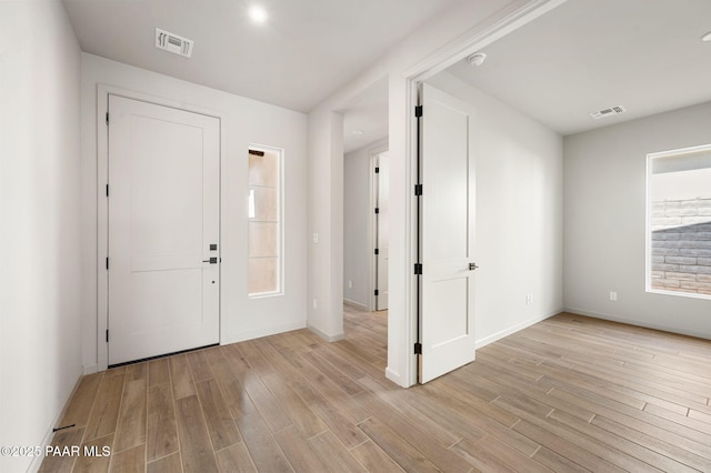 foyer entrance with light wood-type flooring, visible vents, and baseboards