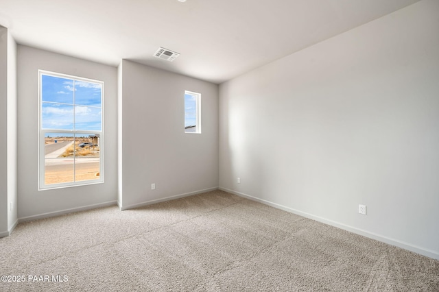 carpeted empty room featuring visible vents and baseboards