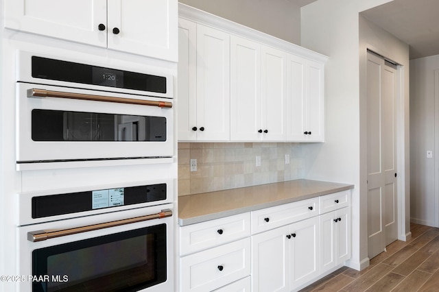 kitchen with light countertops, wood finished floors, white cabinetry, and decorative backsplash