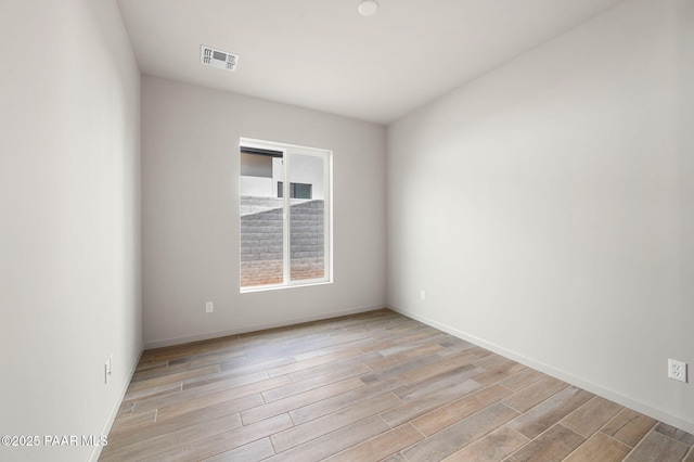 unfurnished room with visible vents, light wood-style flooring, and baseboards