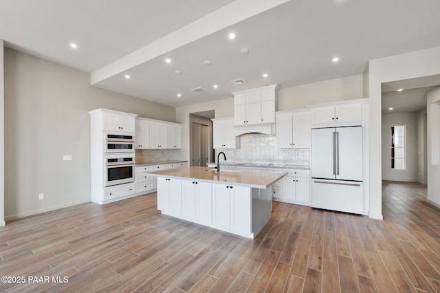 kitchen featuring light countertops, white appliances, an island with sink, and white cabinets