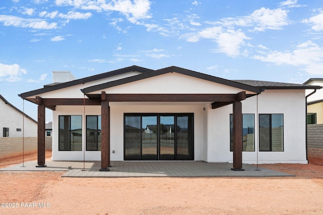 rear view of property with fence, a patio, and stucco siding