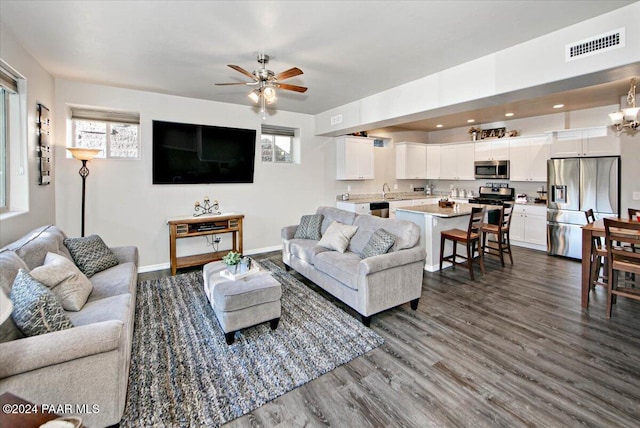 living room featuring ceiling fan with notable chandelier and dark hardwood / wood-style floors