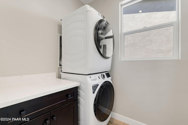 laundry room with cabinets and stacked washing maching and dryer